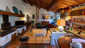 Una sala de estar acogedora con chimenea, un sofá, una mesa de comedor y una estantería llena de libros.