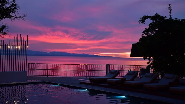 A poolside area with lounge chairs and a view of the sea during sunset. - Hotel Boutique Palma Arena (Turbo)