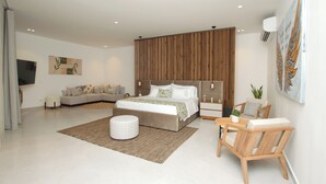 A modern bedroom with a large bed, a sofa, a wooden chair, a small table, and a TV mounted on the wall. - Hotel Boutique Palma Arena (Turbo)