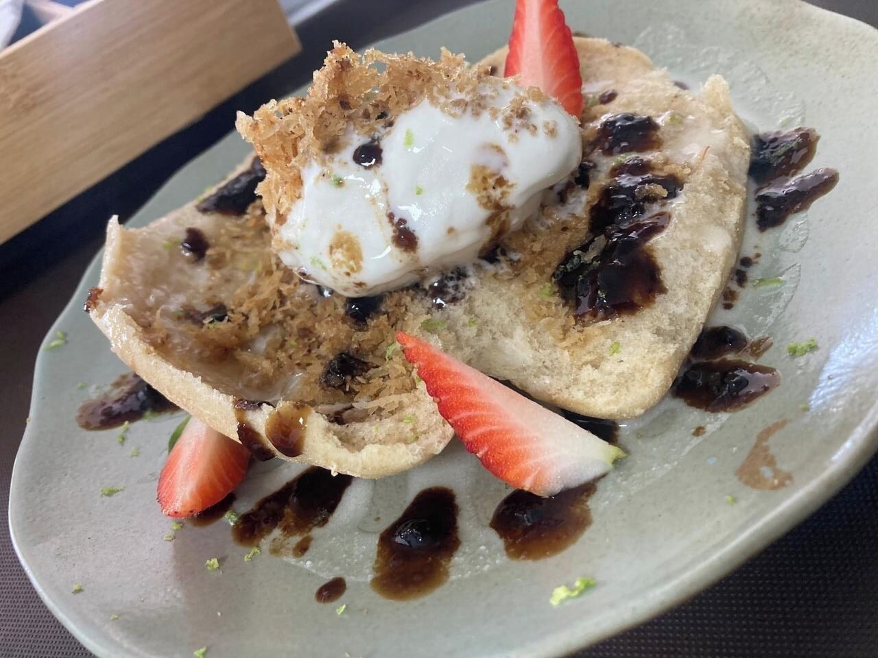 A dessert plate with pancakes, a strawberry, and a dollop of cream.
