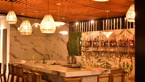 A bar area with a marble countertop, hanging wicker light fixtures, and a green leafy wall. - Hotel Boutique Palma Arena (Turbo)