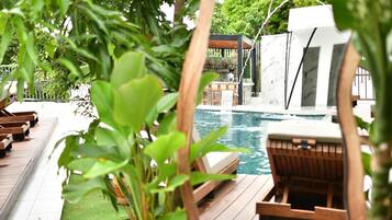 Una piscina al aire libre, sombrillas, sillones reclinables de piscina