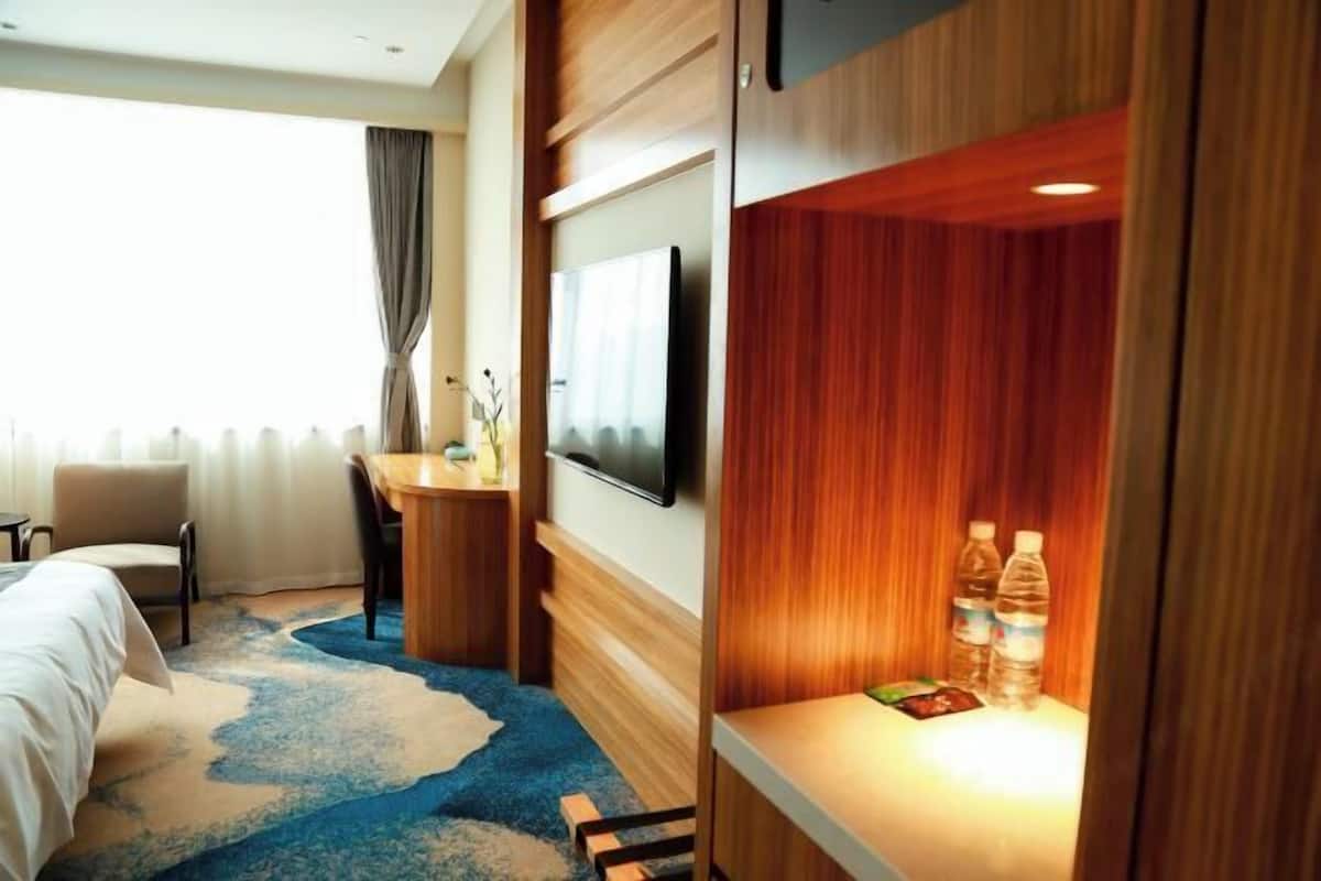 A hotel room with a bed, a desk, a television, and a minibar.