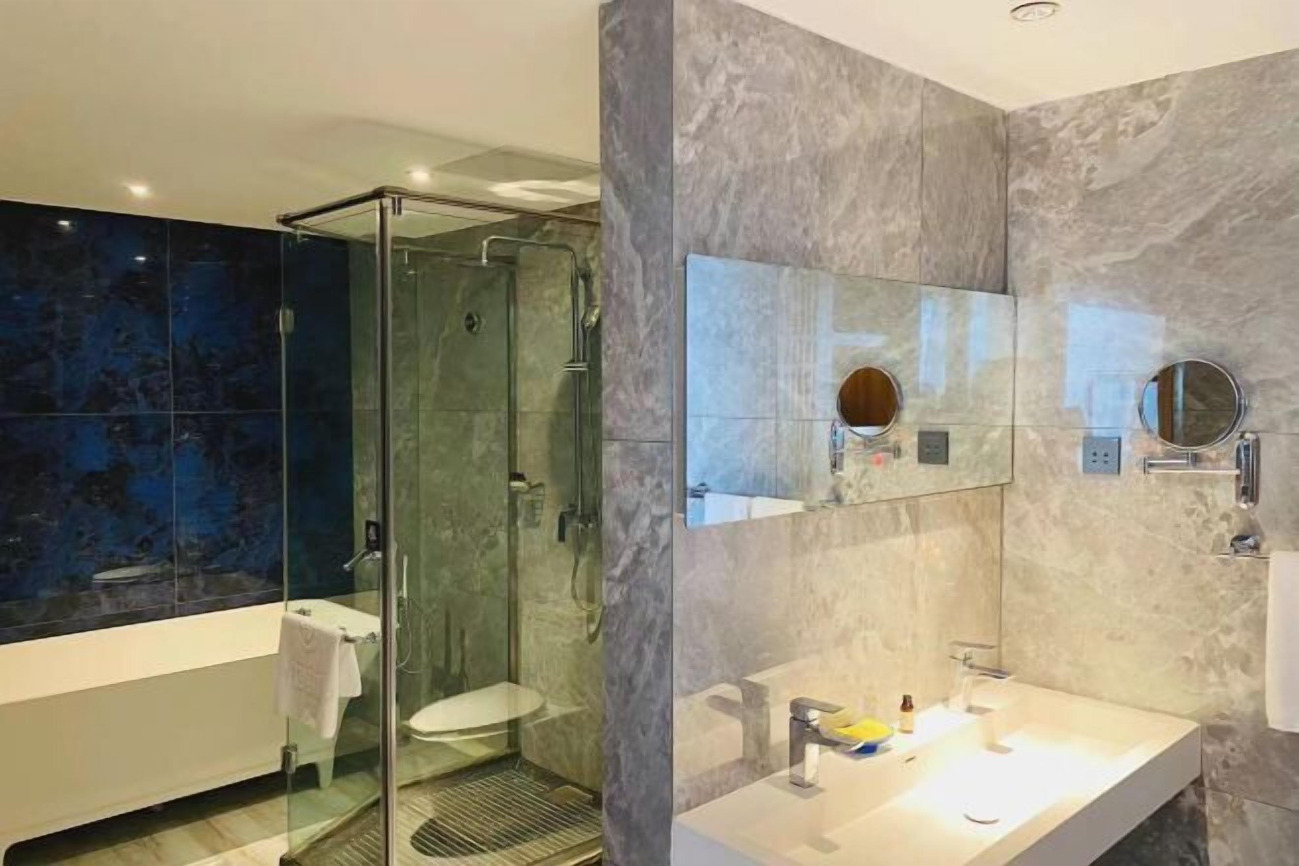 A modern bathroom with a glass-enclosed shower, a white sink, and a large mirror.