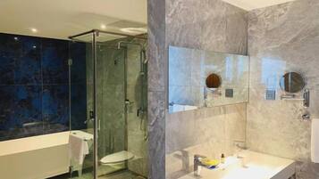 A modern bathroom with a glass-enclosed shower, a white sink, and a large mirror.