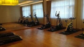 A gym with stationary bikes and treadmills arranged in rows.