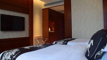 Una habitación de hotel con dos camas, un televisor montado en la pared y un armario de madera.