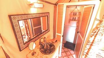Une salle de bain avec un grand miroir, un lavabo orné d’un récipient décoratif et un porte-serviettes.