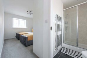 Un dormitorio con cama, ventana, ducha y radiador.