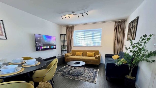 Ett modernt vardagsrum med soffa, soffbord, TV och matplats.