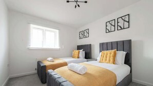 Ett hotellrum med två sängar, ett fönster och konstverk på väggarna.