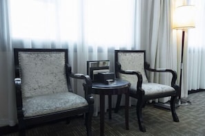 A hotel room with two upholstered chairs, a small round table, and a floor lamp. - Wuyue Hotel (Guiyang)