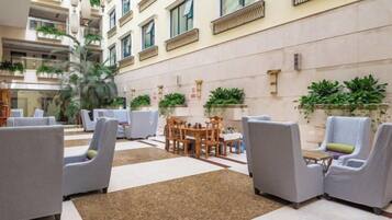 A hotel lobby with seating areas, a central table, and potted plants.