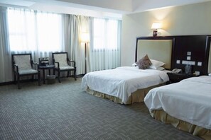 A hotel room with two beds, a desk, chairs, a lamp, and a large mirror. - Wuyue Hotel (Guiyang)