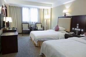 A hotel room with two beds, a desk, a chair, a lamp, and a nightstand. - Wuyue Hotel (Guiyang)
