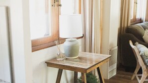 A cozy room with a wooden table, a chair, a lamp, and a window with curtains.