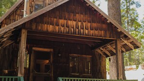 A rustic wooden cabin with a chimney, a porch, and a green railing.
