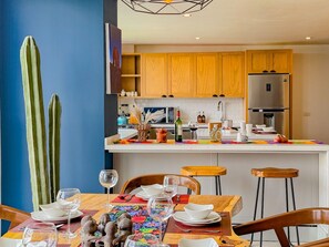 Een moderne keuken met houten kasten, een roestvrijstalen koelkast en een eethoek met een tafel gedekt voor twee personen.