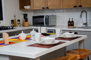 Een moderne keuken met een centraal eiland, een magnetron, een spoelbak en houten kastjes.