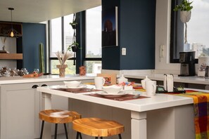Een moderne keuken met een centraal eiland, barstoelen en uitzicht op de stad.