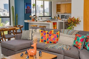 Ein modernes Wohnzimmer mit einem grauen Sofa, bunten Kissen und einer dekorativen Hirschfigur.