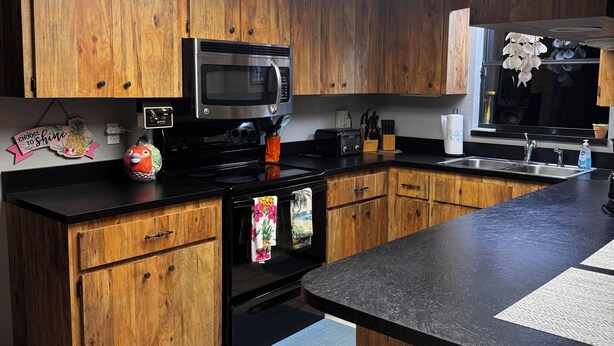 Una cocina con armarios de madera, un microondas, una estufa y un lavamanos.