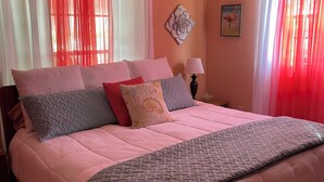 Un dormitorio con una cama grande, un ventilador de techo y cortinas rojas.