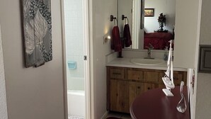 Un baño con tocador de madera, espejo y alfombra roja.