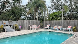 Una piscina con cubierta de madera, rodeada por una cerca de madera y árboles.
