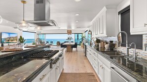 A modern kitchen with a large island, stainless steel appliances, and a view of the ocean. - Beachfront Boho Dream Penthouse. Walk 2 Everything!   Newly designed  SLEEPS 10! (Oceanside)