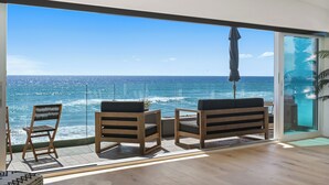 A balcony with a view of the ocean, wooden chairs, and a potted plant. - Beachfront Boho Dream Penthouse. Walk 2 Everything!   Newly designed  SLEEPS 10! (Oceanside)