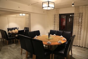 Une salle de conférence avec une table ronde, des chaises noires et un lustre.