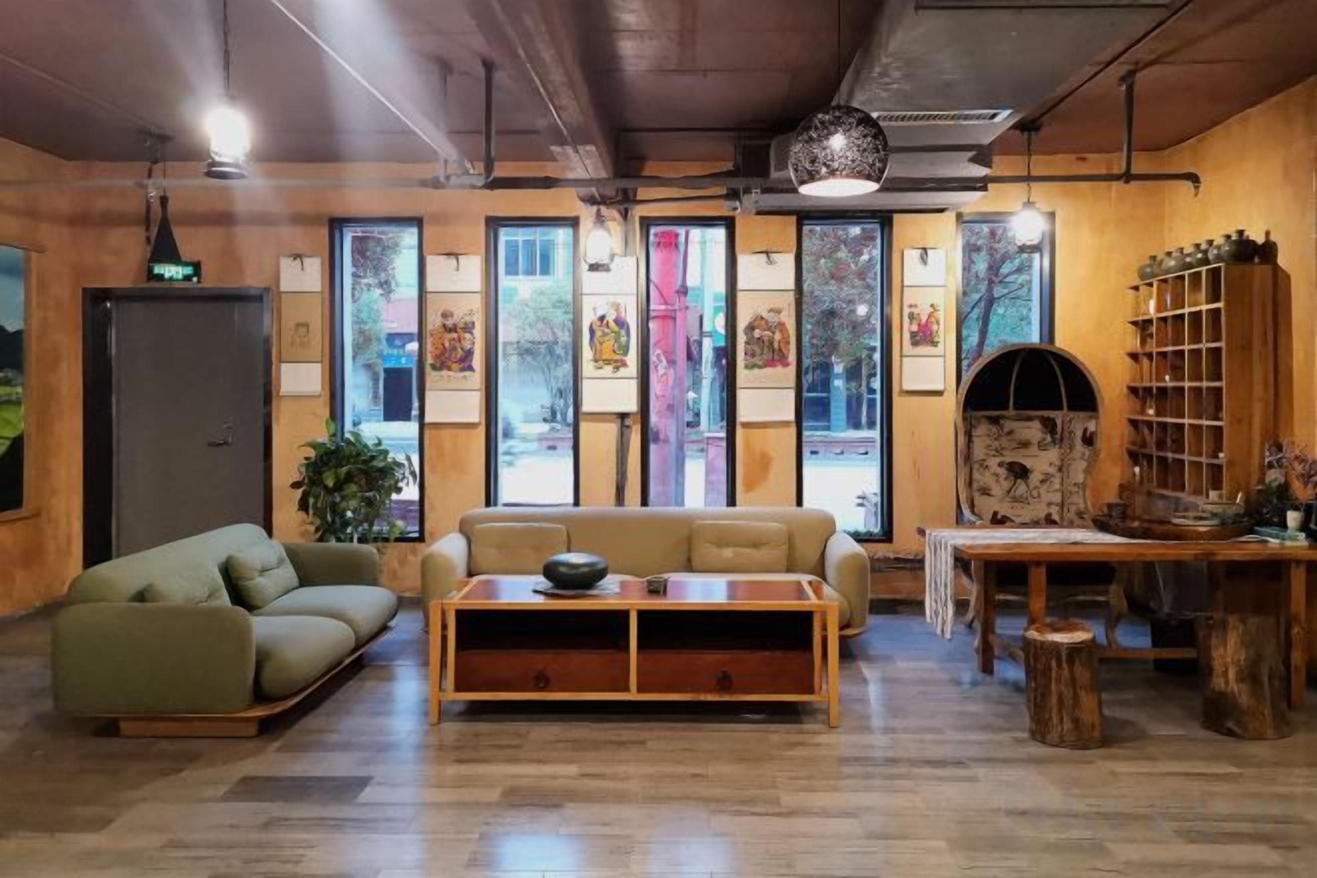 A room with a sofa, a table, and a bookshelf. There are windows with artwork and a door.
