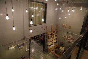 Ein Zimmer mit einem hölzernen Bücherregal, einem Spiegel und hängenden Glühbirnen.