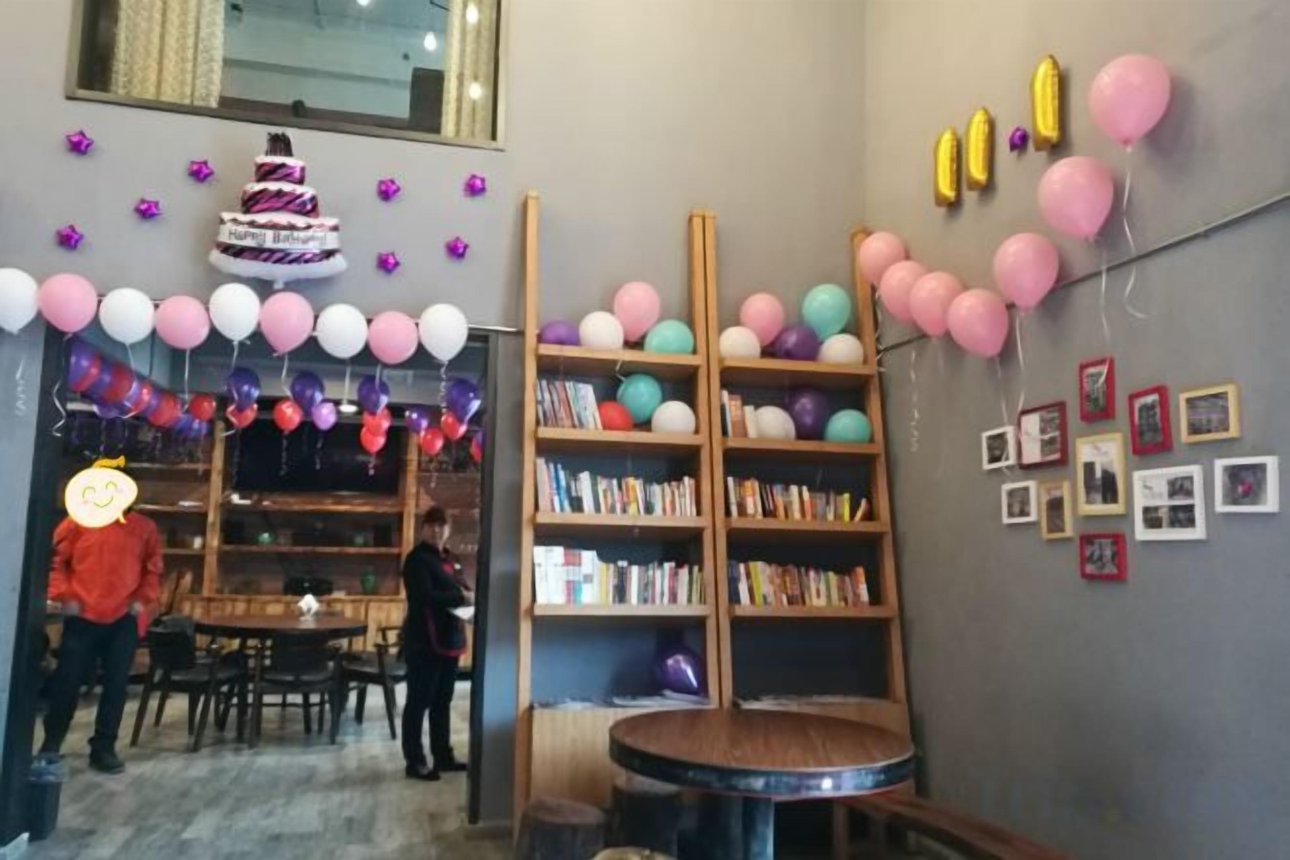 Una habitación con una mesa redonda, estanterías y globos.
