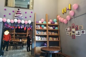 A room with a round table, bookshelves, and balloons.