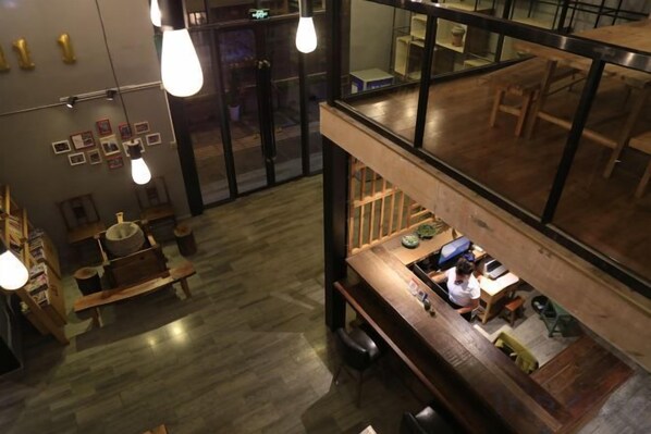 An interior view of a restaurant with a wooden bar area, hanging light fixtures, and a view through a glass partition.