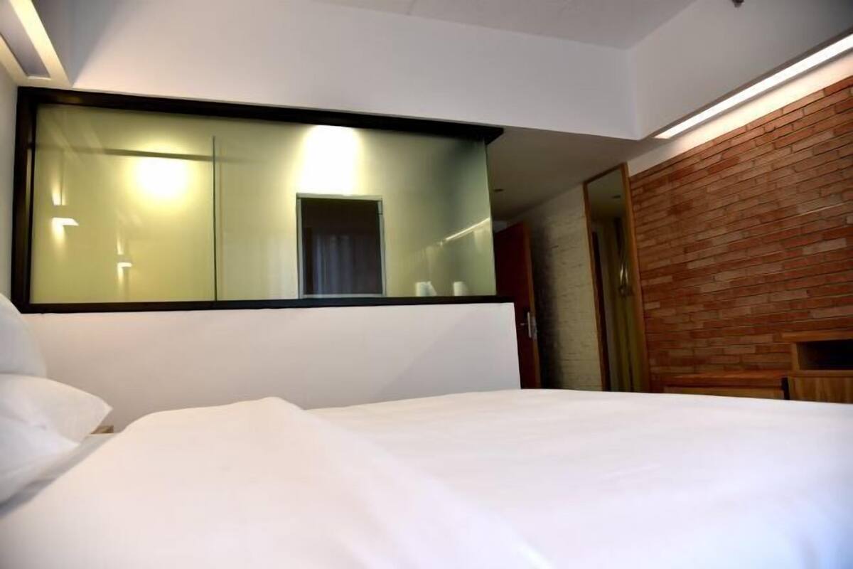 Ein Hotelzimmer mit einem großen Bett, einem Spiegel, einer Holzwand und einer Tür.