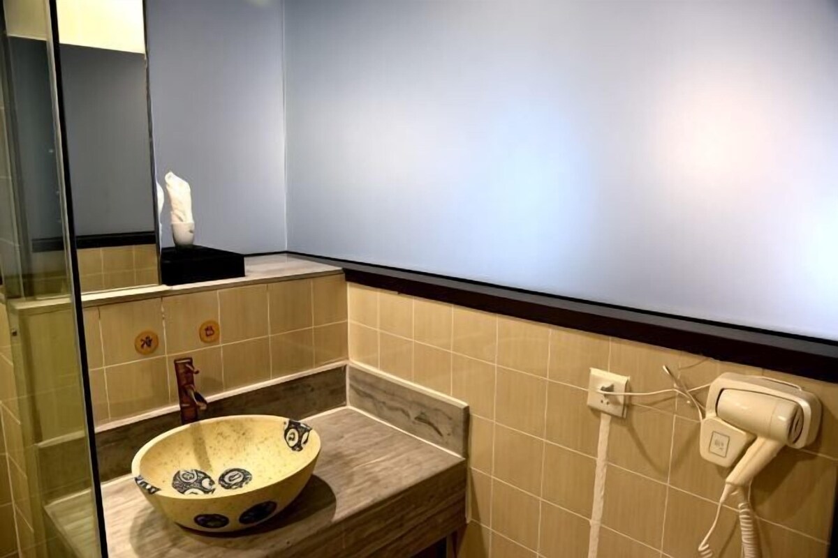 A bathroom with a bowl sink, a hairdryer, and a mirror.
