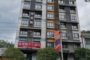 Ein mehrstöckiges Gebäude mit Balkonen und einem auffälligen, roten Schild, das ein Hotel bewirbt.