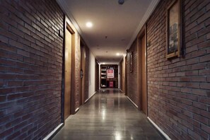 A corridor with brick walls and wooden doors, leading to a reception area with a sign. - Pingtang Yazhou Tao Art Hotel (Pingtang)