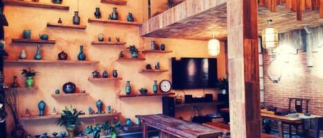 Una habitación con varias estanterías que exhiben diversos objetos, un banco de madera y un televisor.