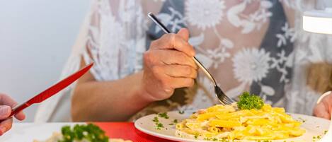 A person dining with a plate of pasta and a fork.