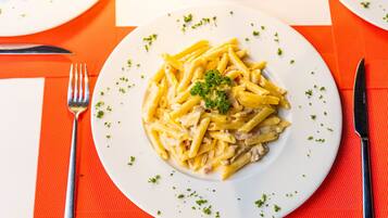 A plate of pasta with a garnish, placed on a table with a red placemat.