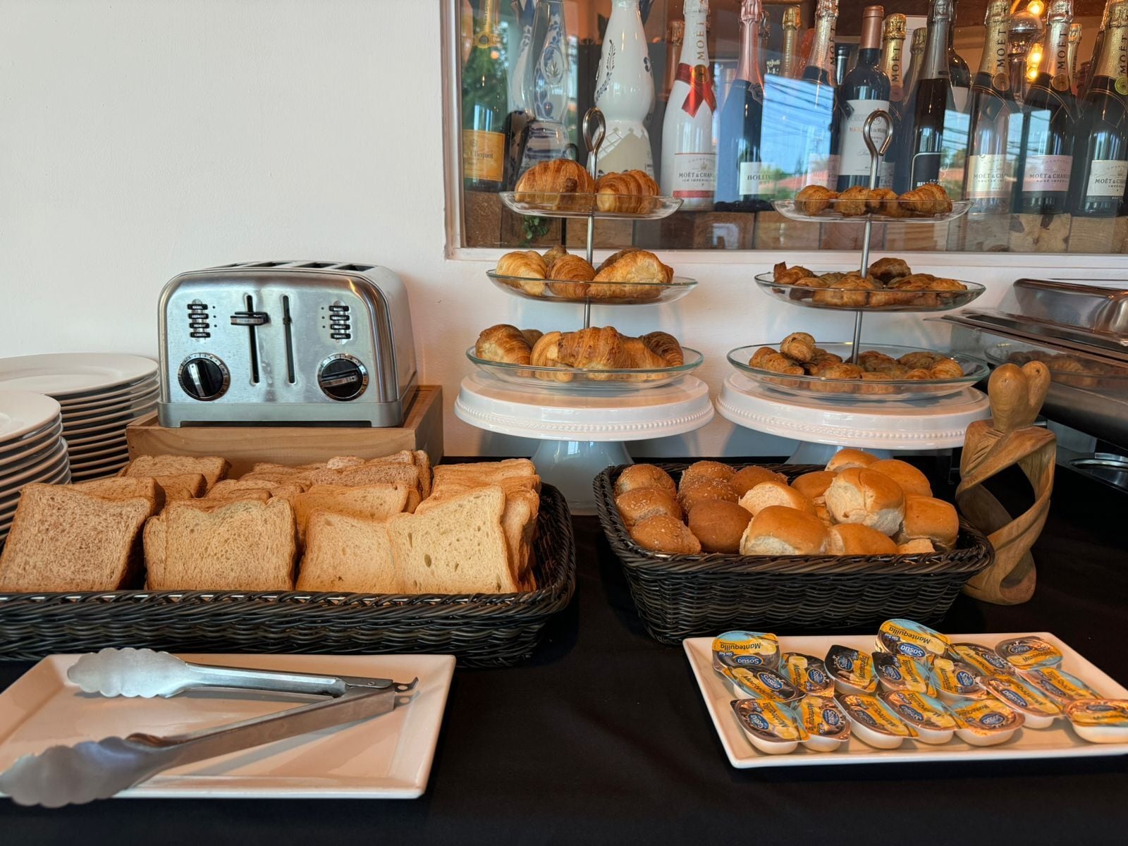 A breakfast buffet with bread, pastries, and a toaster.