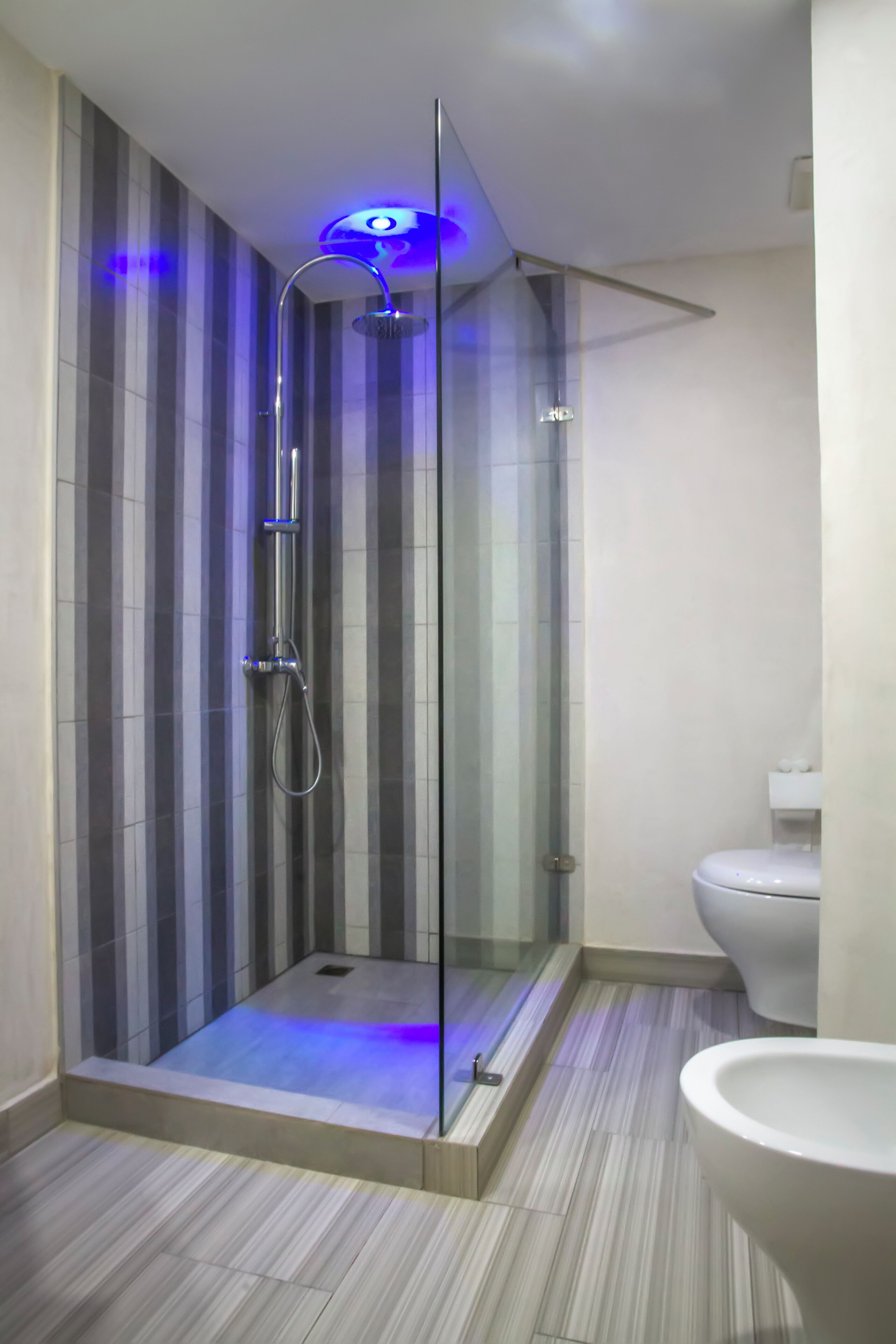 A modern bathroom with a glass-enclosed shower, a toilet, and a sink.