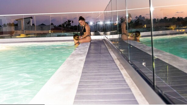 A swimming pool with glass railings and a tiled deck. - Hotel Alkquimia (Bayahibe)