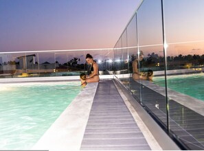 A swimming pool with glass railings and a tiled deck. - Hotel Alkquimia (Bayahibe)