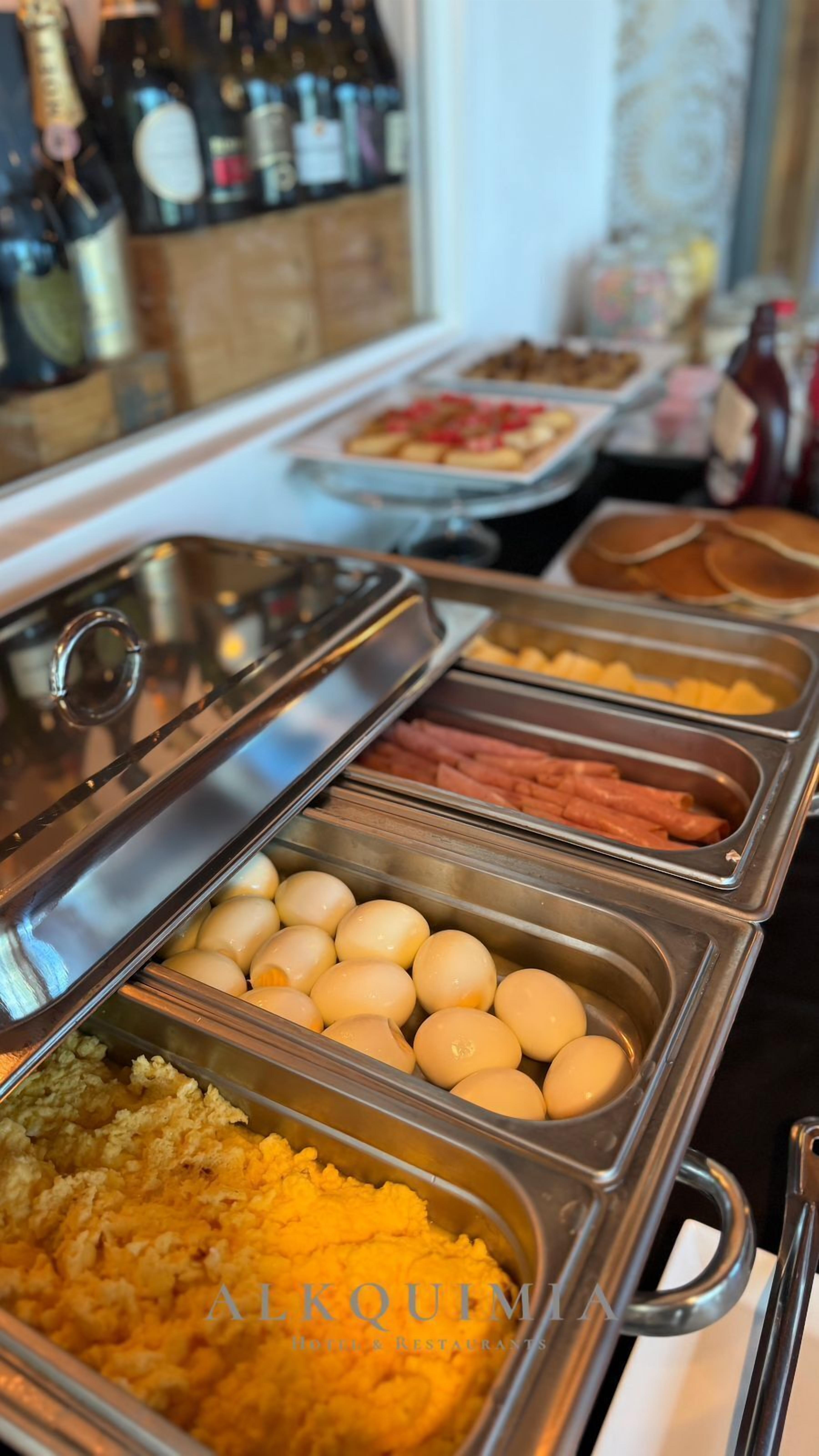 En buffet med forskellige retter, herunder æg, skinke og kartoffelmos.