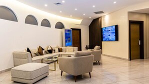 A modern living room with a sectional sofa, a glass coffee table, and a flat-screen TV mounted on the wall. - Hotel Alkquimia (Bayahibe)